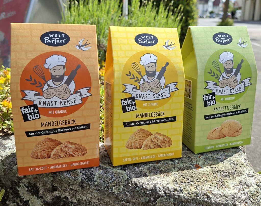 Bild mit drei Kekspackungen, die die drei Geschmacksrichtungen Mandelgebäck mit Orange, Mandelgebäck mit Zitrone und Amarettigebäck zeigen.