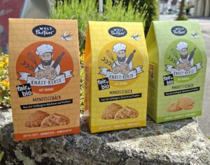 Bild mit drei Kekspackungen, die die drei Geschmacksrichtungen Mandelgebäck mit Orange, Mandelgebäck mit Zitrone und Amarettigebäck zeigen.