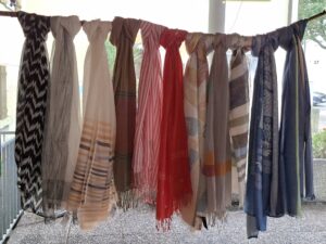11 unterschiedliche Sommerschals, drappiert auf einem Bambusstock